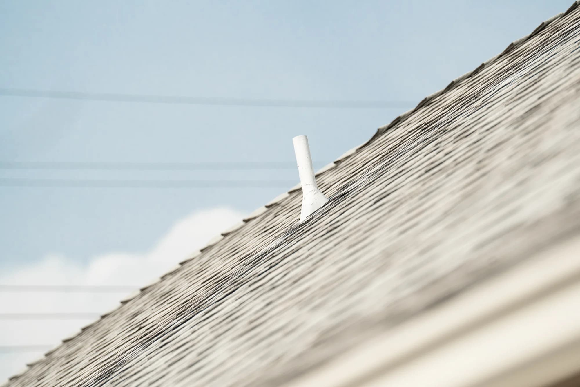 Close-up view of asphalt roof shingles and a roof vent